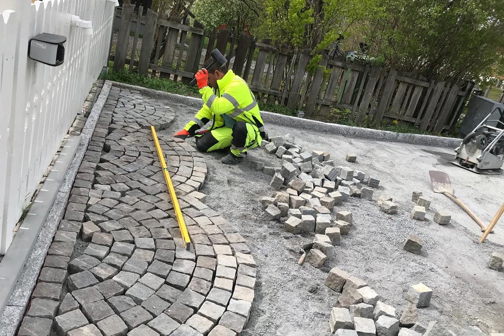 Man som lägger sten utanför hus